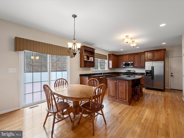 dining space featuring light wood-type flooring, sink, and an inviting chandelier