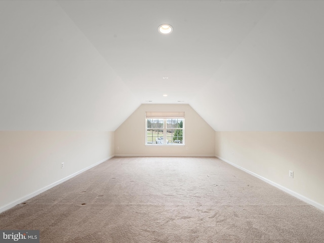 bonus room with lofted ceiling and light carpet