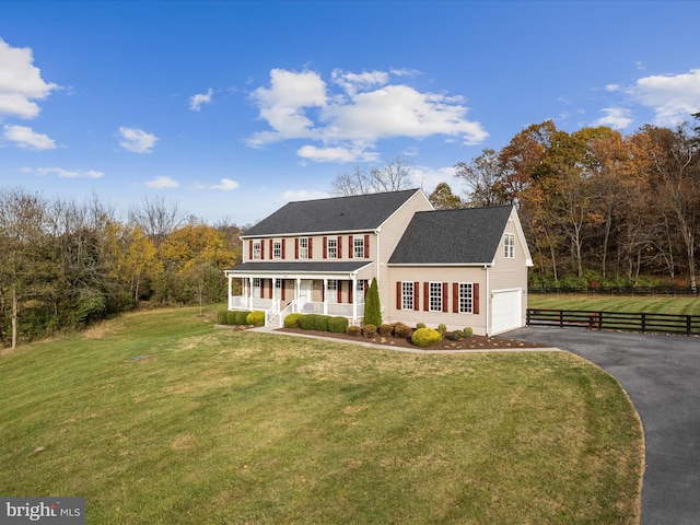 view of front of home featuring a front lawn, covered porch, and a garage