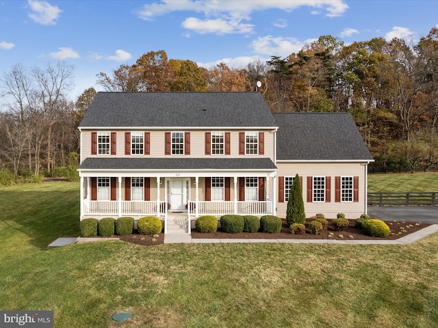 colonial-style house featuring a porch and a front yard