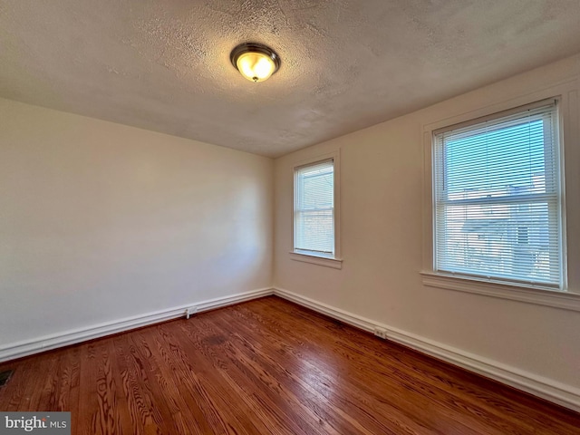 unfurnished room with hardwood / wood-style floors and a textured ceiling