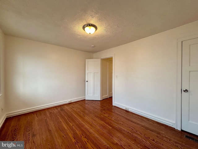 empty room featuring wood-type flooring and a textured ceiling