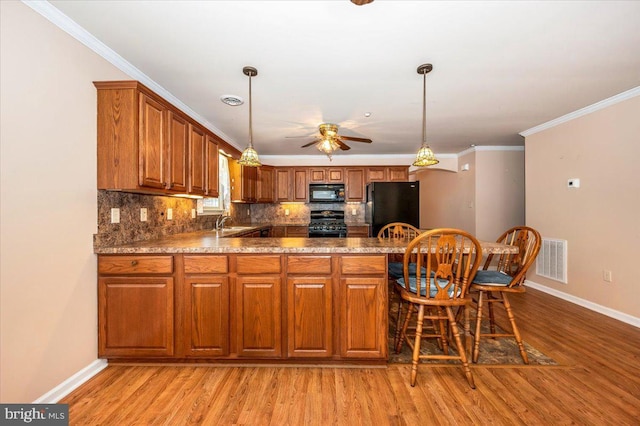 kitchen featuring black appliances, light wood-type flooring, sink, and ornamental molding