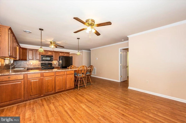 kitchen with black appliances, sink, hanging light fixtures, light hardwood / wood-style flooring, and tasteful backsplash