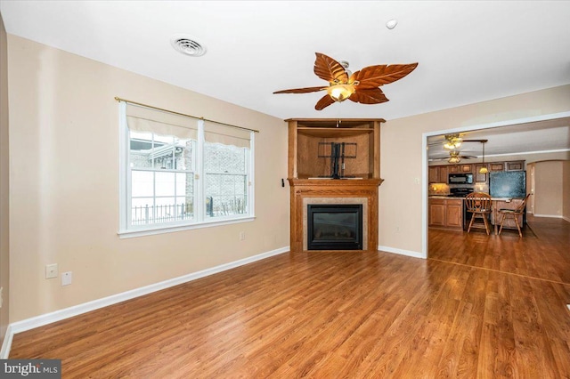 unfurnished living room featuring ceiling fan and hardwood / wood-style flooring