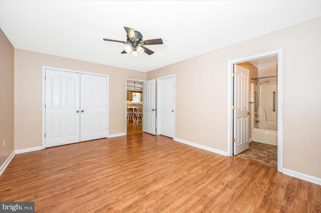 unfurnished bedroom with ceiling fan, ensuite bathroom, and light hardwood / wood-style flooring