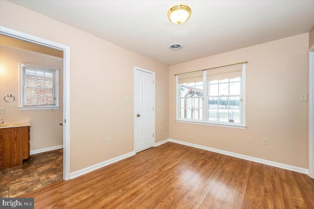 unfurnished bedroom with a closet, multiple windows, and dark hardwood / wood-style floors