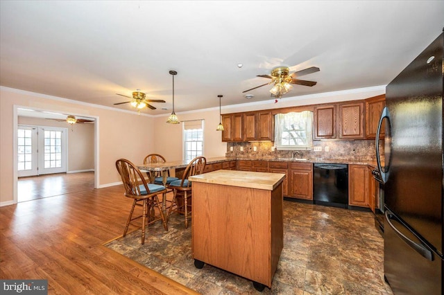 kitchen featuring pendant lighting, backsplash, black appliances, ornamental molding, and a kitchen island