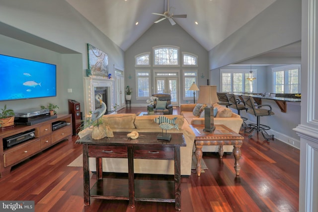 living room with a premium fireplace, dark hardwood / wood-style flooring, high vaulted ceiling, and ceiling fan