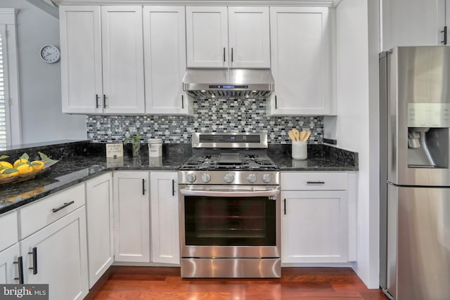 kitchen with dark stone counters, white cabinets, stainless steel appliances, and extractor fan