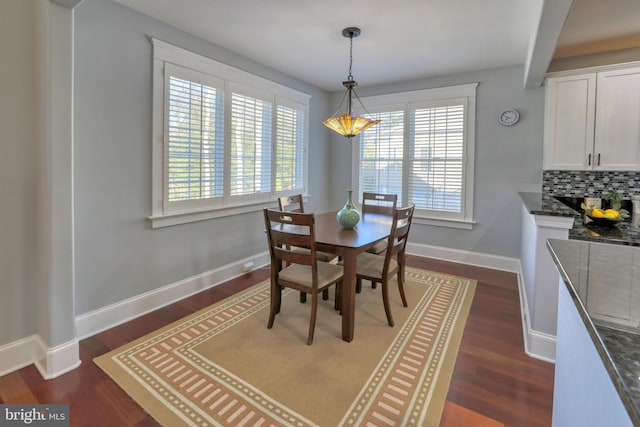 dining space featuring beam ceiling and dark hardwood / wood-style flooring