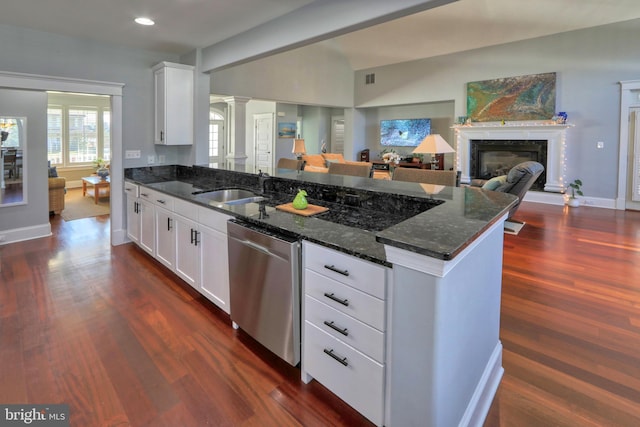 kitchen featuring white cabinets, sink, stainless steel dishwasher, and dark stone countertops