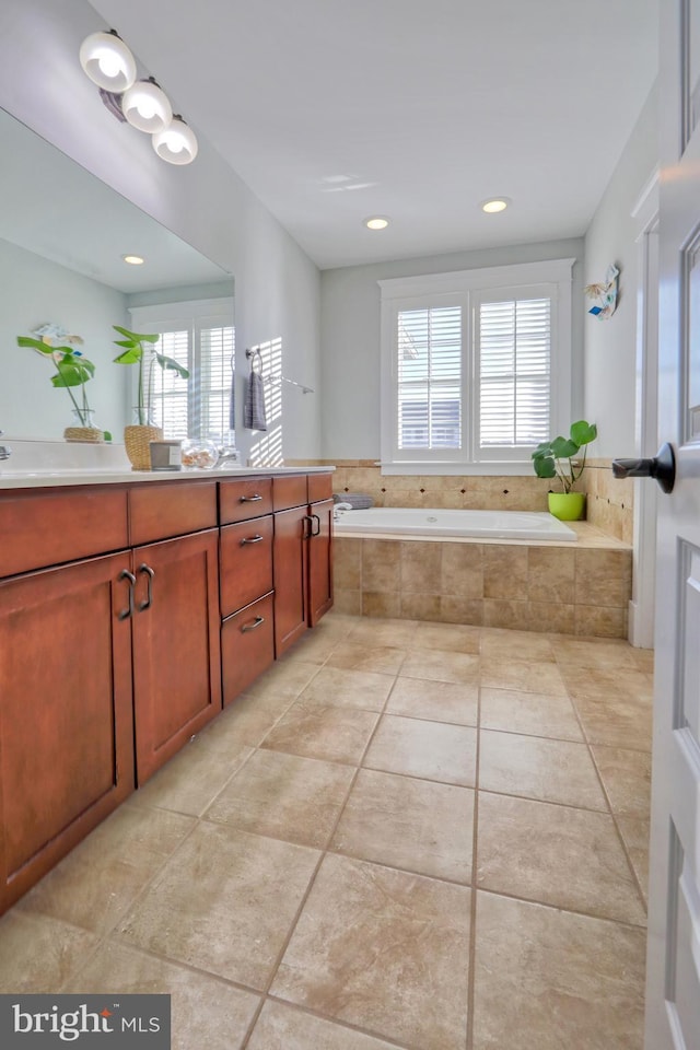 bathroom featuring tile patterned flooring, plenty of natural light, a relaxing tiled tub, and vanity