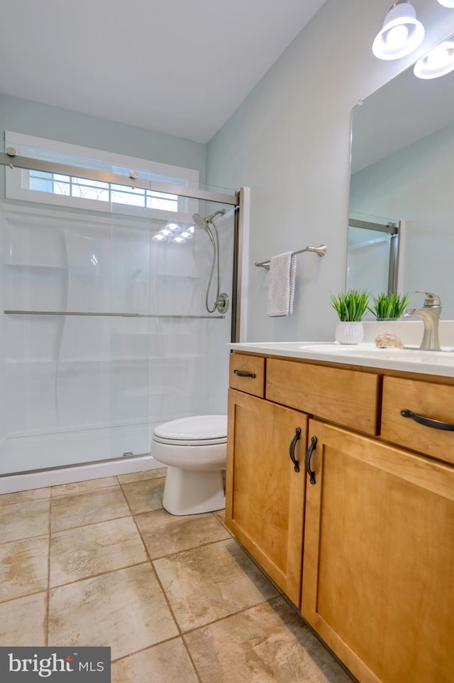 bathroom with tile patterned flooring, vanity, toilet, and an enclosed shower