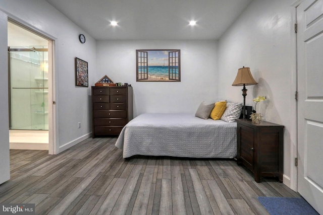 bedroom with ensuite bath and wood-type flooring