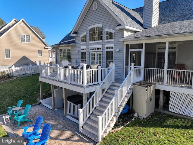 back of property with a lawn, a wooden deck, a sunroom, and a patio