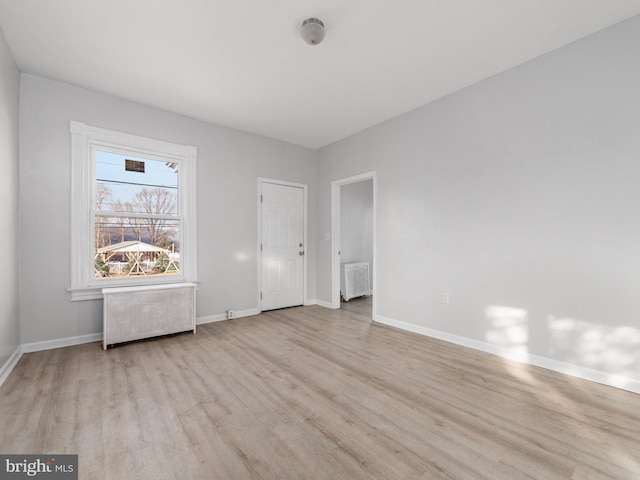 unfurnished room with light wood-type flooring and radiator