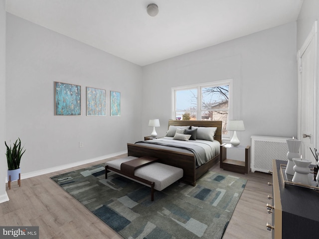 bedroom with radiator heating unit and light hardwood / wood-style floors