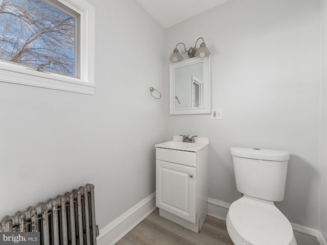 bathroom featuring radiator heating unit, vanity, toilet, and hardwood / wood-style floors