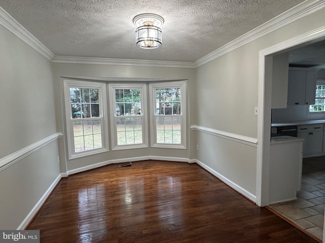 unfurnished dining area featuring dark hardwood / wood-style floors, a healthy amount of sunlight, ornamental molding, and a textured ceiling