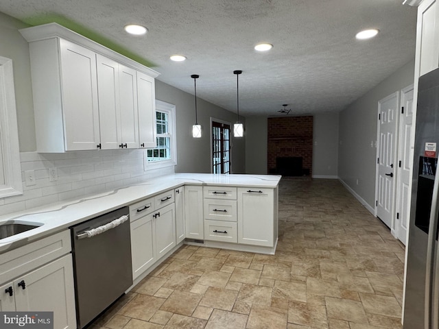 kitchen featuring kitchen peninsula, white cabinets, a brick fireplace, dishwasher, and hanging light fixtures