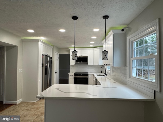 kitchen with kitchen peninsula, sink, stainless steel appliances, and decorative light fixtures