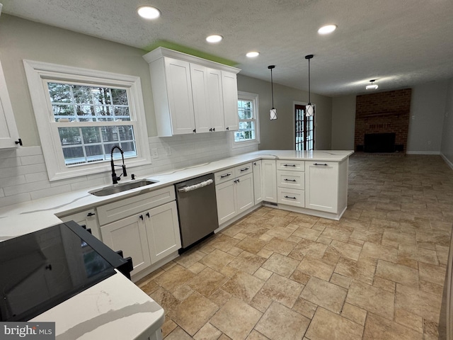 kitchen with white cabinets, stainless steel dishwasher, sink, decorative light fixtures, and a fireplace