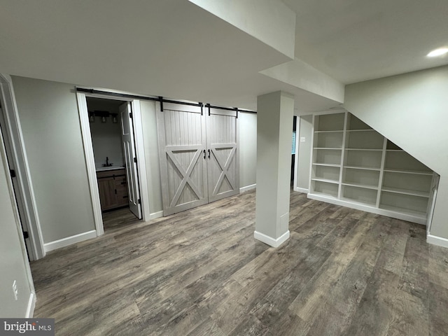 basement featuring hardwood / wood-style floors, a barn door, and sink