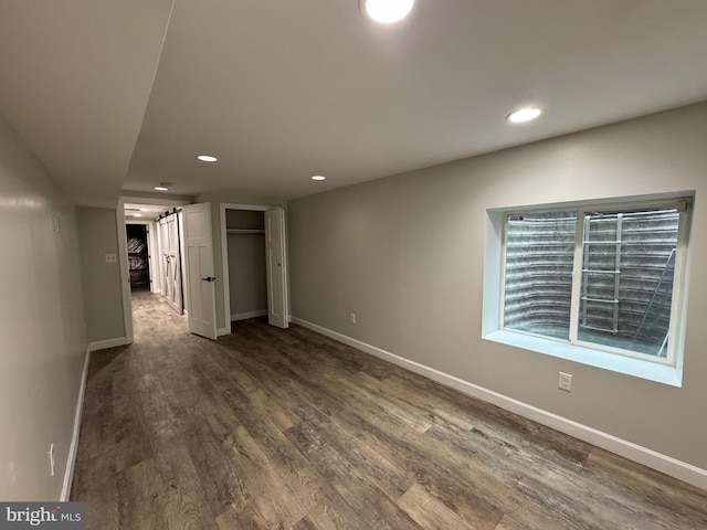 unfurnished bedroom with hardwood / wood-style floors and a barn door