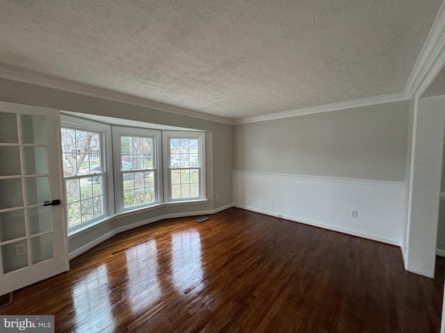 empty room with a textured ceiling, ornamental molding, and dark wood-type flooring