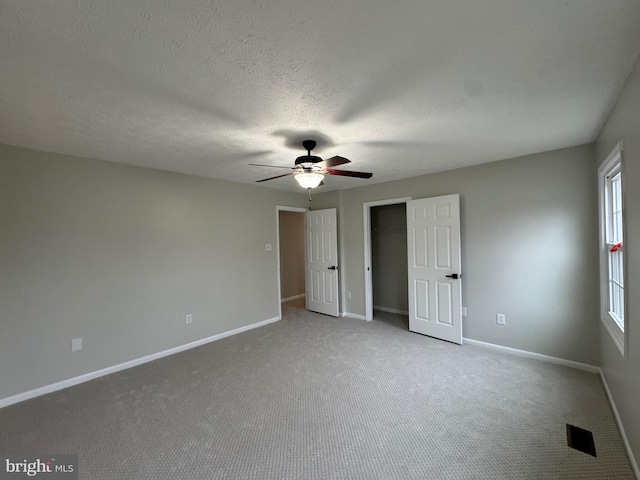 unfurnished bedroom with ceiling fan, carpet, and a textured ceiling