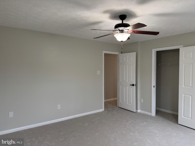 unfurnished bedroom with a closet, a textured ceiling, light colored carpet, and ceiling fan