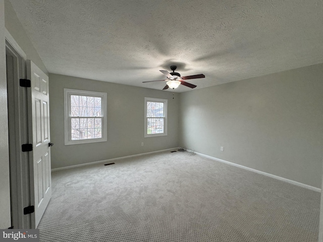 empty room with a textured ceiling, light colored carpet, and ceiling fan