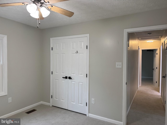 unfurnished bedroom with light carpet, a textured ceiling, and ceiling fan