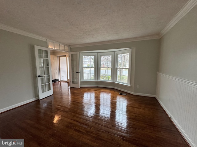 spare room with a textured ceiling, french doors, dark hardwood / wood-style floors, and ornamental molding