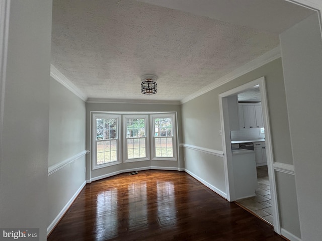 unfurnished dining area featuring dark hardwood / wood-style flooring, a textured ceiling, and ornamental molding