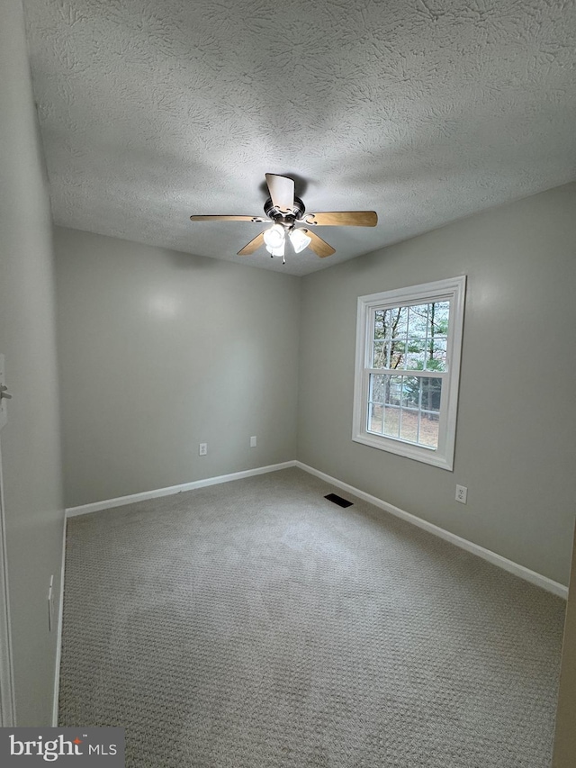 carpeted empty room featuring ceiling fan and a textured ceiling