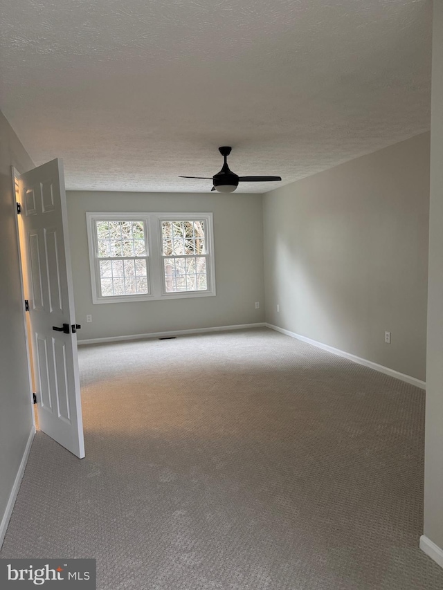 carpeted spare room featuring ceiling fan and a textured ceiling