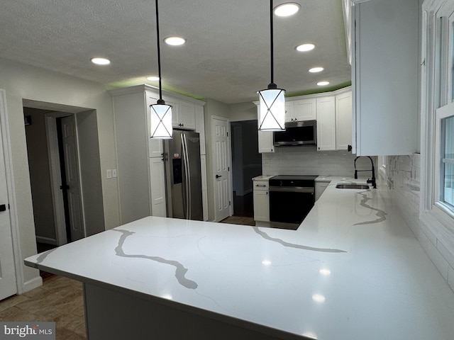 kitchen with kitchen peninsula, appliances with stainless steel finishes, hanging light fixtures, and sink