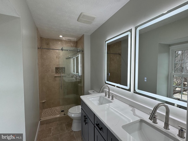 bathroom with tile patterned flooring, a textured ceiling, toilet, and a shower with door