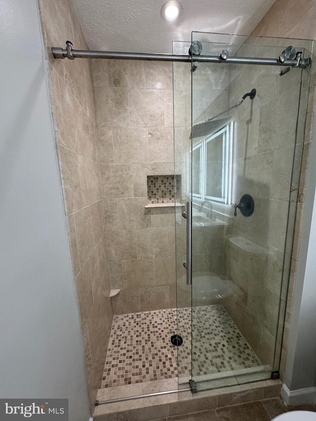 bathroom with a textured ceiling and a shower with door