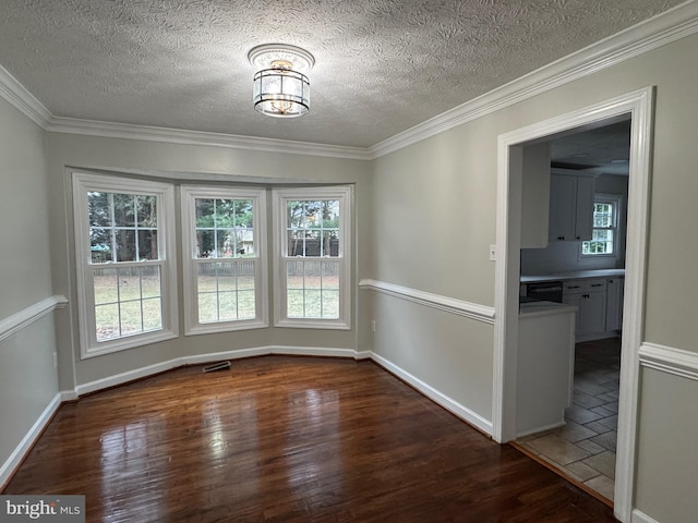 unfurnished dining area featuring dark hardwood / wood-style flooring, a textured ceiling, and ornamental molding