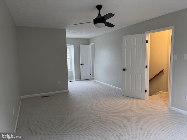 empty room featuring light carpet, ceiling fan, and a textured ceiling