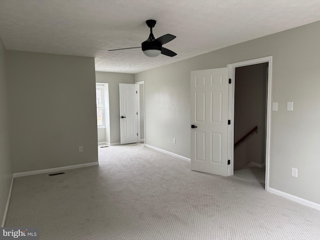 unfurnished bedroom featuring ceiling fan, light carpet, and a textured ceiling