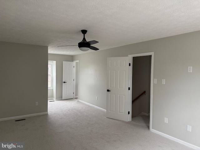 spare room with light carpet, ceiling fan, and a textured ceiling