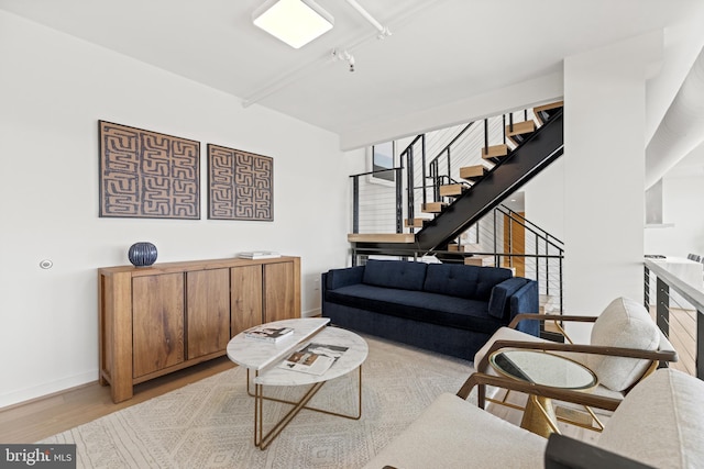 living area featuring baseboards, wood finished floors, and stairs