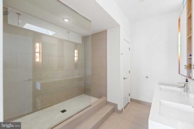 full bath featuring tile patterned floors, a walk in shower, baseboards, and a sink