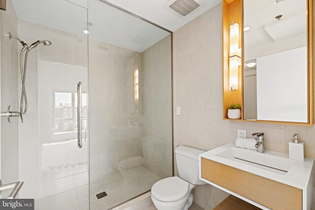 full bath with visible vents, toilet, tile walls, and a shower stall