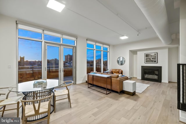 living room featuring a glass covered fireplace, a view of city, light wood-style flooring, and floor to ceiling windows