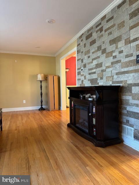 unfurnished living room with crown molding, a fireplace, and wood-type flooring